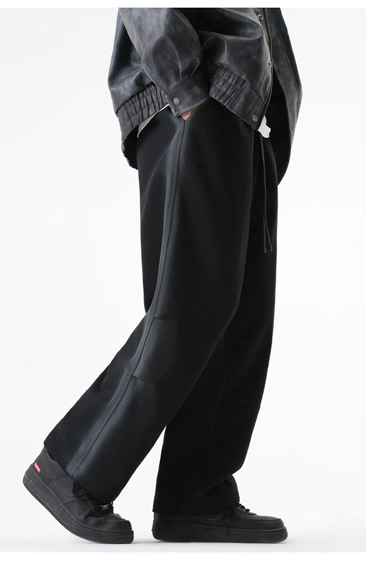 Side view of black wide-leg drawstring pants worn with a gray jacket and black sneakers