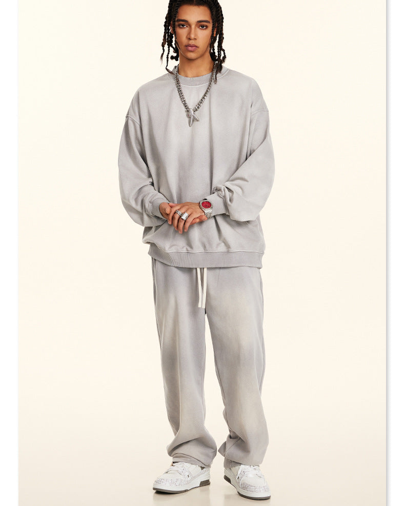 Full-length casual grey sweatsuit set with drawstring pants and oversized crewneck, styled with white sneakers