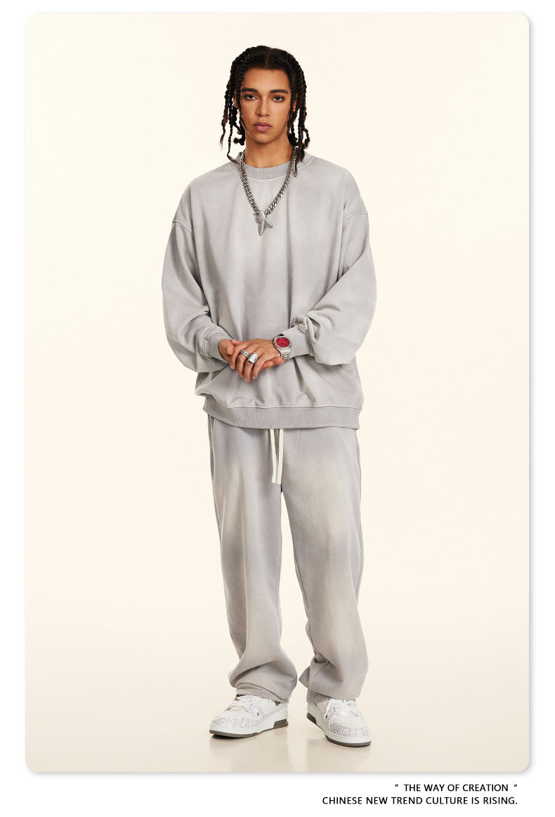 Full-length casual grey sweatsuit set with drawstring pants and oversized crewneck, styled with white sneakers