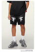 Close-up of black cotton shorts with white cupid angel graphics, shown with white socks and gray chunky sneakers
