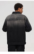 The rear angle of a black washed denim jacket showing its ombre fade design and relaxed fit