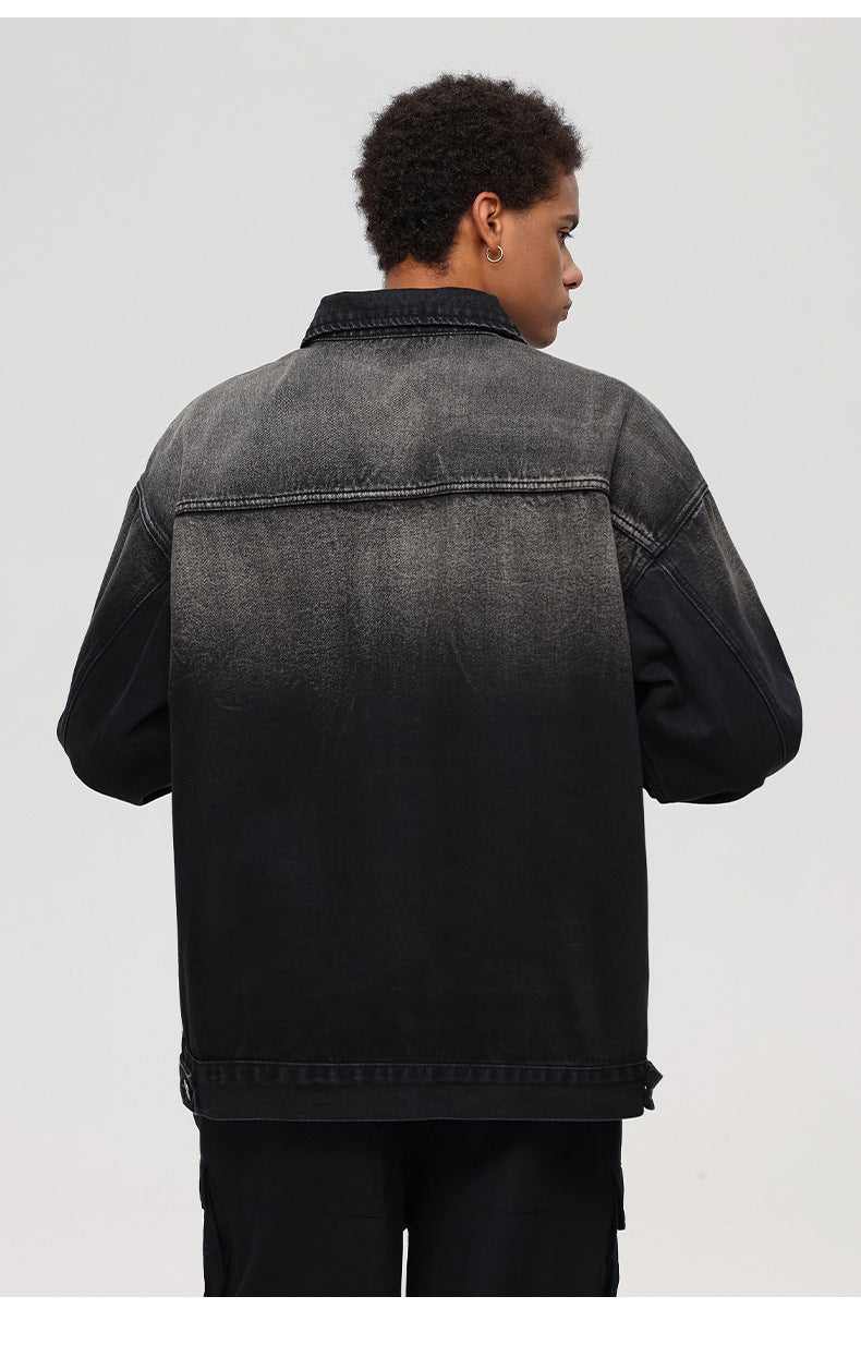 The rear angle of a black washed denim jacket showing its ombre fade design and relaxed fit