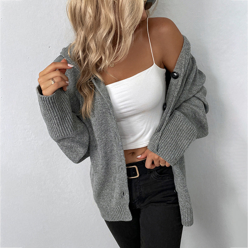 Gray knit cardigan styled with a white one-shoulder top, black high-waisted jeans, and a gold buckle belt, showcasing a casual chic look