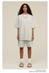 Woman with curly hair modeling white oversized T-shirt and shorts set with beige slide sandals