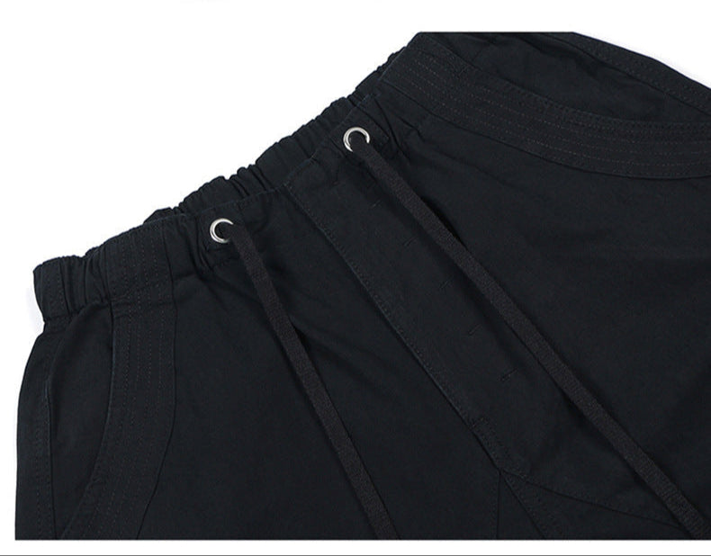 Close-up of black elastic waistband with drawstring closure and metal eyelets on casual cargo pants against white background