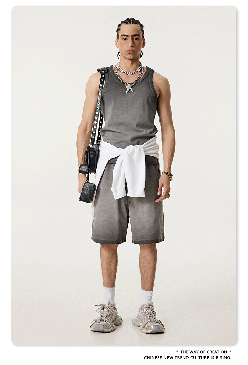 Male model wearing a gray ombre tank top and matching shorts with a white sweater tied at the waist, accessorized with silver jewelry and sneakers