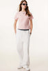 Female model in white wide-leg sweatpants with a contrast waistband, paired with a pink tee and sneakers for a casual look.