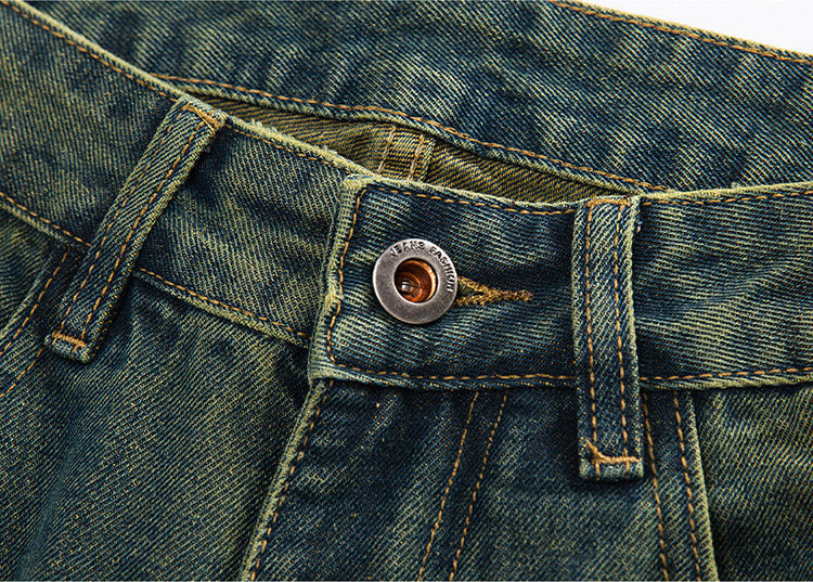 A detailed shot of the waistband and button of vintage-wash denim jeans, with visible stitching and a metal button