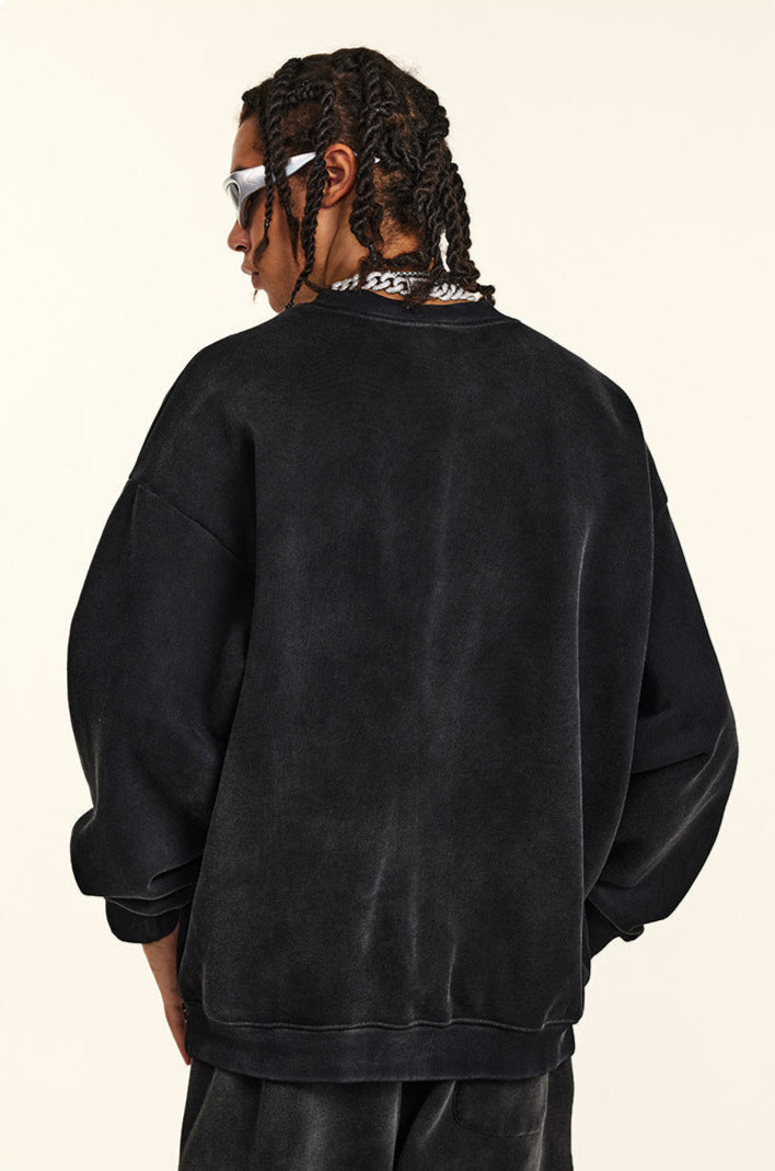 Side profile of model with twisted braids wearing black oversized sweatshirt, white-framed sunglasses, silver chain necklace, washed vintage finish