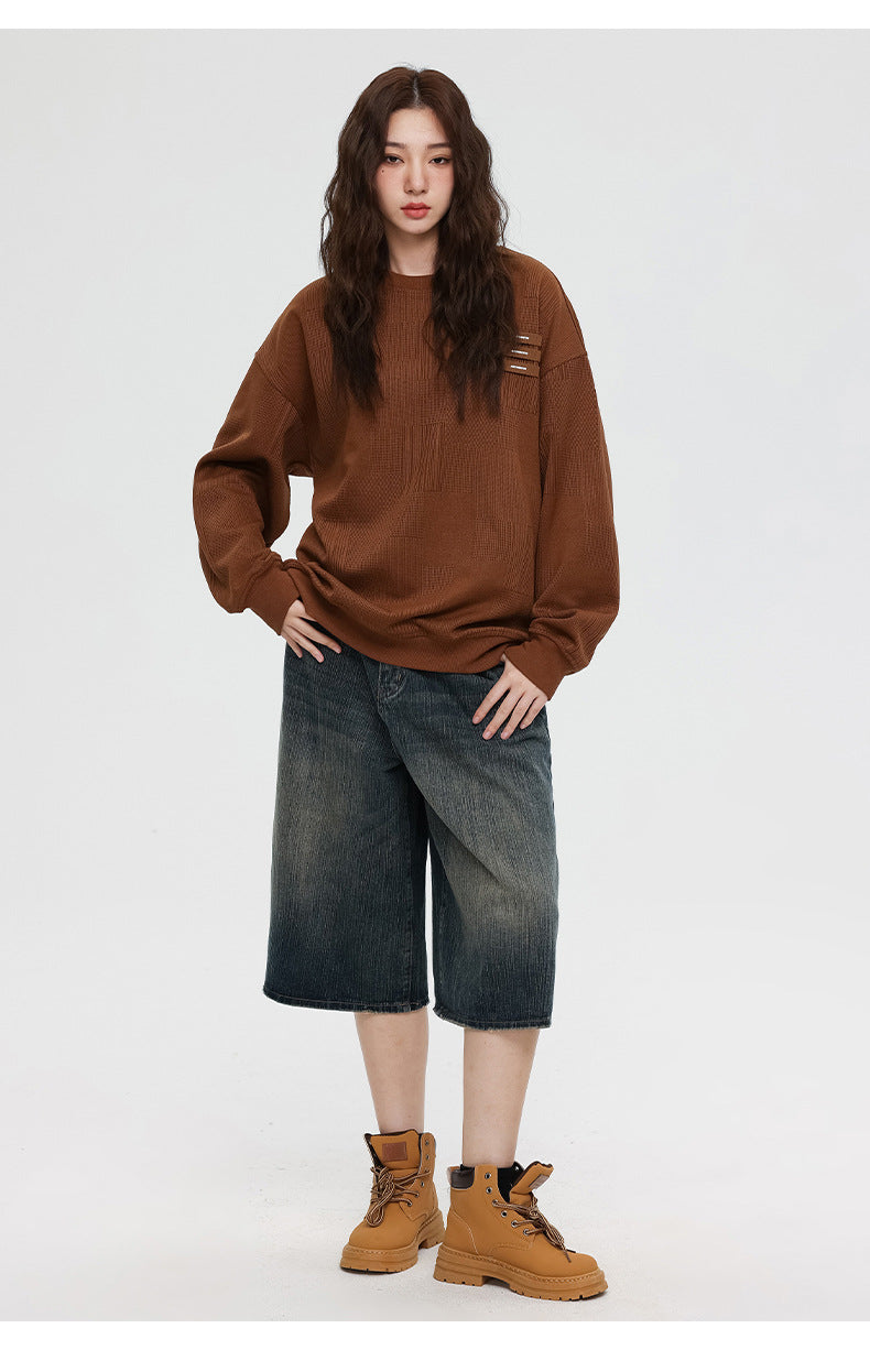 Woman wearing brown textured sweatshirt with denim culottes and tan work boots, hand on hip