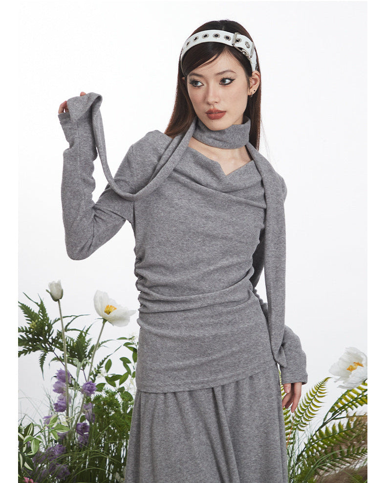 Close-up of gray knit dress showing draped neckline construction and ruched side detail