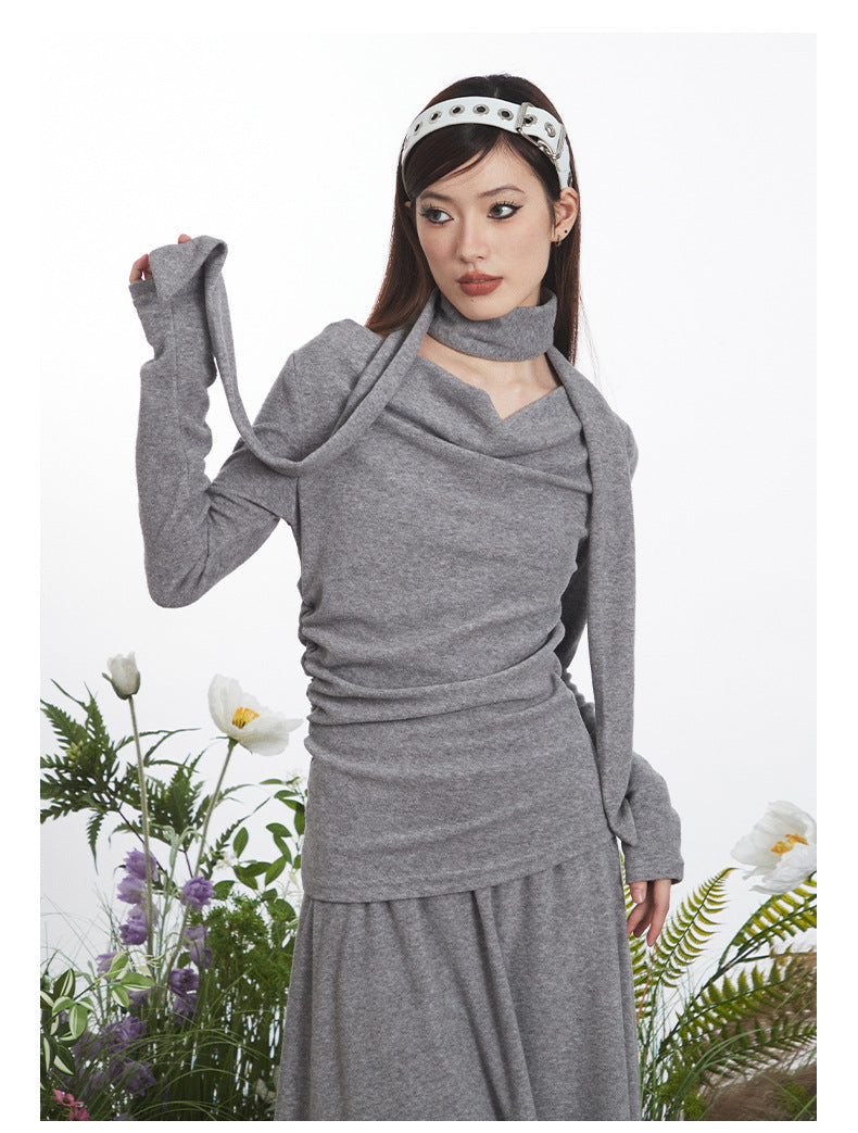 Close-up of gray knit dress showing draped neckline construction and ruched side detail