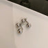 A pair of silver double-ball stud earrings with a reflective surface, displayed on a glossy white surface.