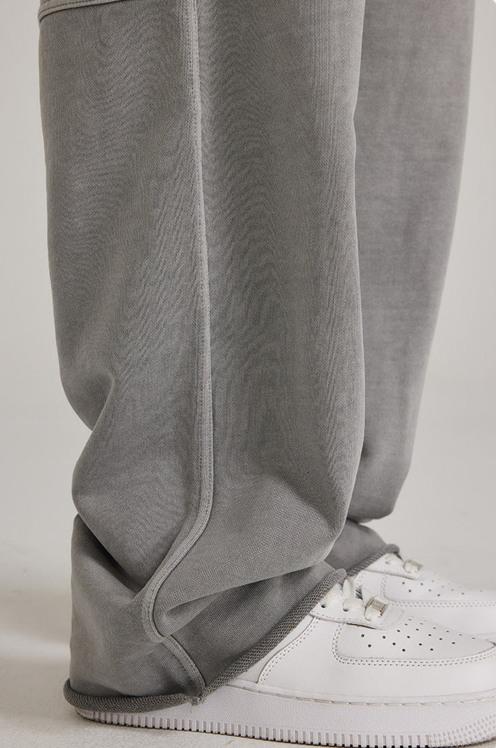 Detail shot of grey sweatpants hem and seam construction, showing relaxed fit over white Air Force 1 sneakers