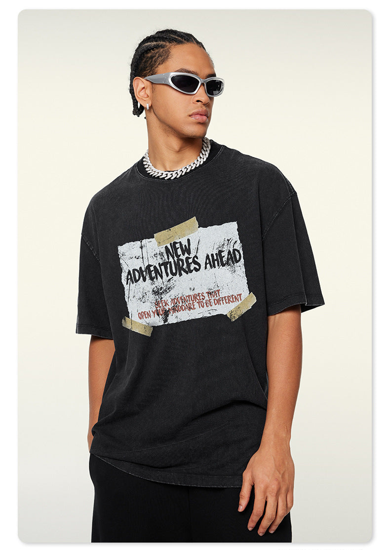 Close-up of model in silver-framed sunglasses wearing black graphic t-shirt with inspirational adventure quote design