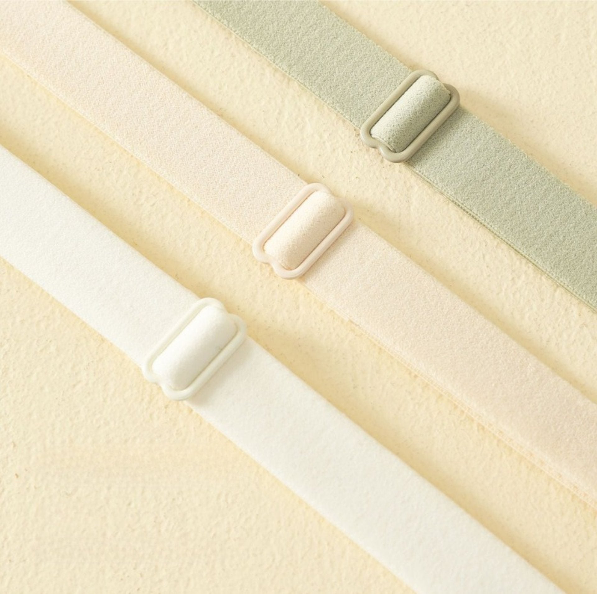 Three elastic adjustable bra straps in cream, beige, and green, showcasing high-stretch material for comfort.