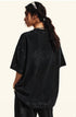 Back view of model showing black t-shirt with ponytail hairstyle against white backdrop