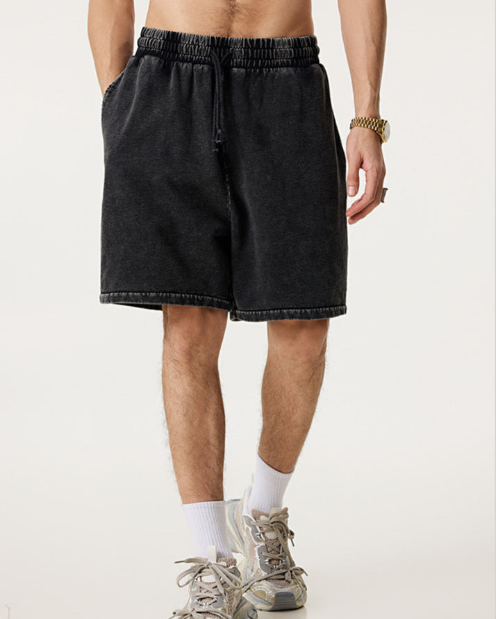 Image 1: "A man wearing black vintage wash athletic shorts with elastic waistband standing with white socks and chunky sneakers against neutral background