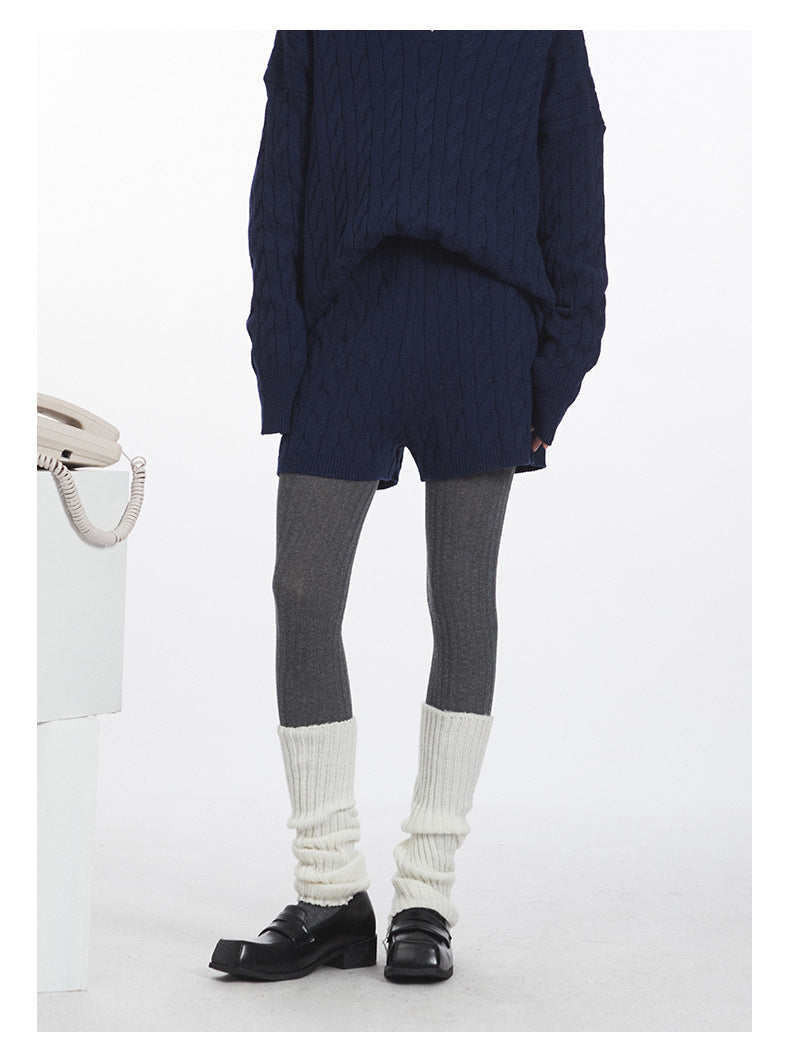 Lower body detail showing navy knit shorts styled with grey tights and white leg warmers.