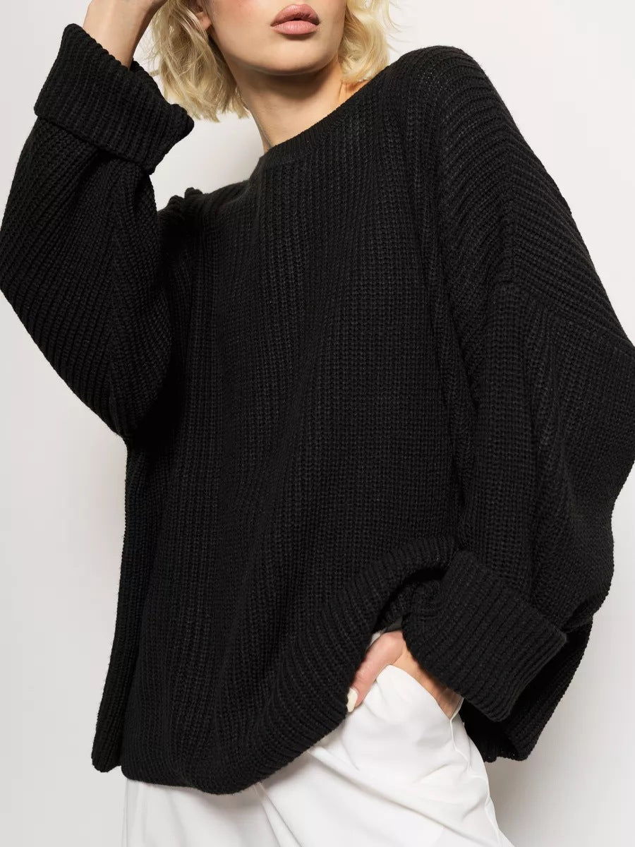 Close-up of black chunky knit sweater with ribbed texture against white background