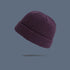 A plum purple ribbed knit beanie with folded cuff floating against slate gray background, displaying rich-colored winter hat