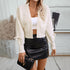 A woman wearing an ivory open-front cropped cardigan with decorative sleeve ties over white crop top and black leather mini skirt