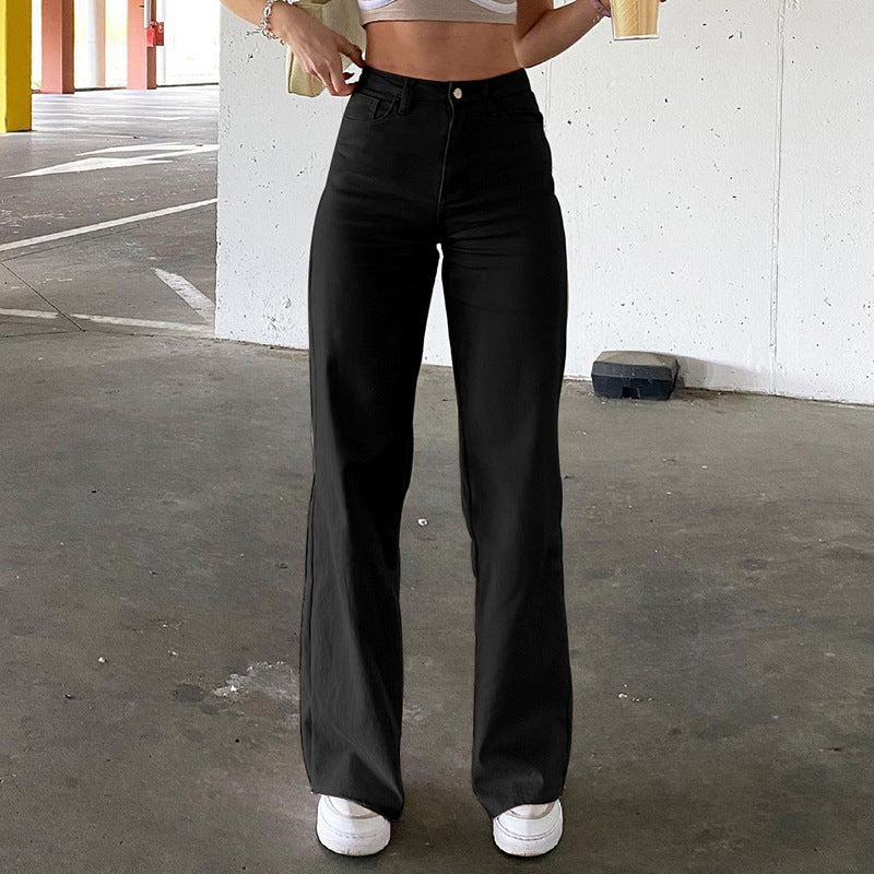 Black high-waisted straight-leg jeans with traditional pocket styling, paired with white sneakers in parking garage setting