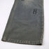 Side view of wide-leg gray jeans hem showing embroidered 'H' logo detail and distressed finish