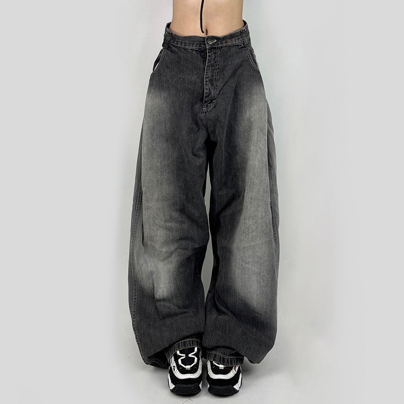 A model wearing washed gray ultra-wide leg jeans with black and white sneakers, front view against white backdrop
