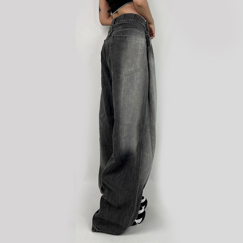 Side profile of gray oversized wide-leg jeans, showing relaxed fit silhouette and black and white chunky sneakers