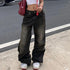 Female model wearing black washed wide-leg jeans with a vintage fade effect, styled with a cropped white top and sneakers