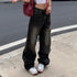 Female model in black vintage-style wide-leg jeans featuring a washed effect, styled with a white crop top and chunky sneakers