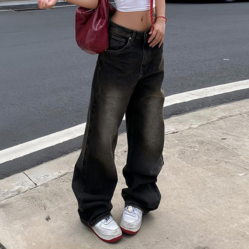 Female model in black vintage-style wide-leg jeans featuring a washed effect, styled with a white crop top and chunky sneakers