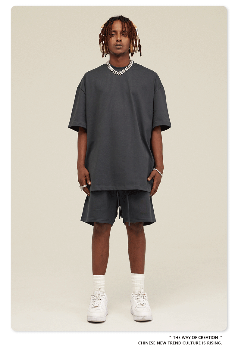 Man wearing charcoal gray oversized T-shirt and shorts set with white Air Force 1 sneakers