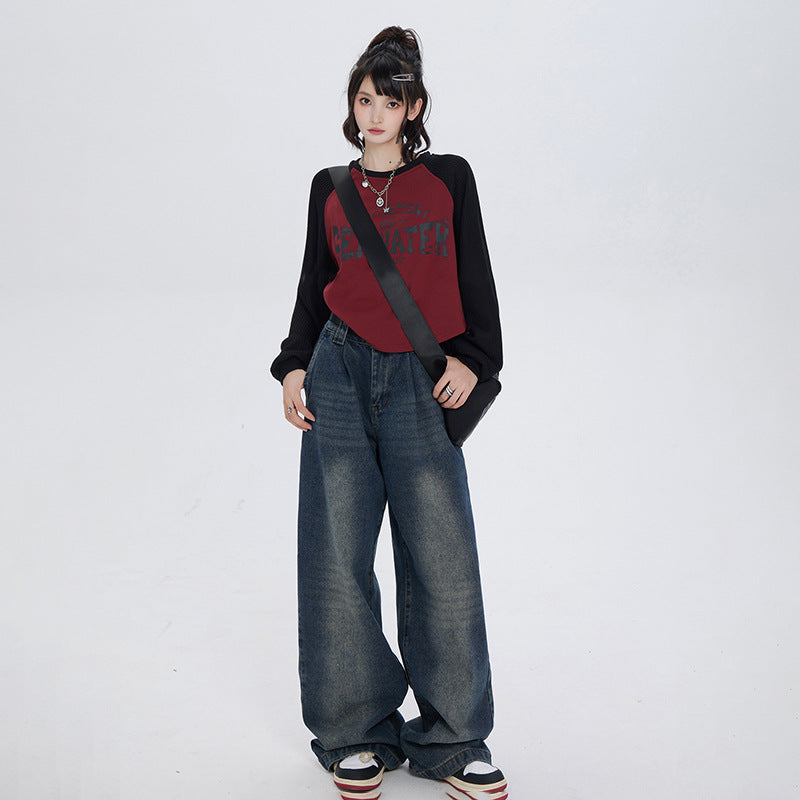 Full-length view of model in baggy wide-leg jeans, burgundy baseball tee with black sleeves and crossbody bag against white backdrop