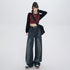 Model with updo hairstyle wearing cropped burgundy top with black sleeves, wide-leg dark denim jeans and black belt on white background