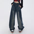 Model wearing ultra-wide leg medium-wash jeans with hands in pockets, burgundy crop top and platform shoes against white background