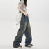 Side view of model in grey graphic crop top, wide-leg jeans with vertical stripe detail and white chain-strap bag against white backdrop