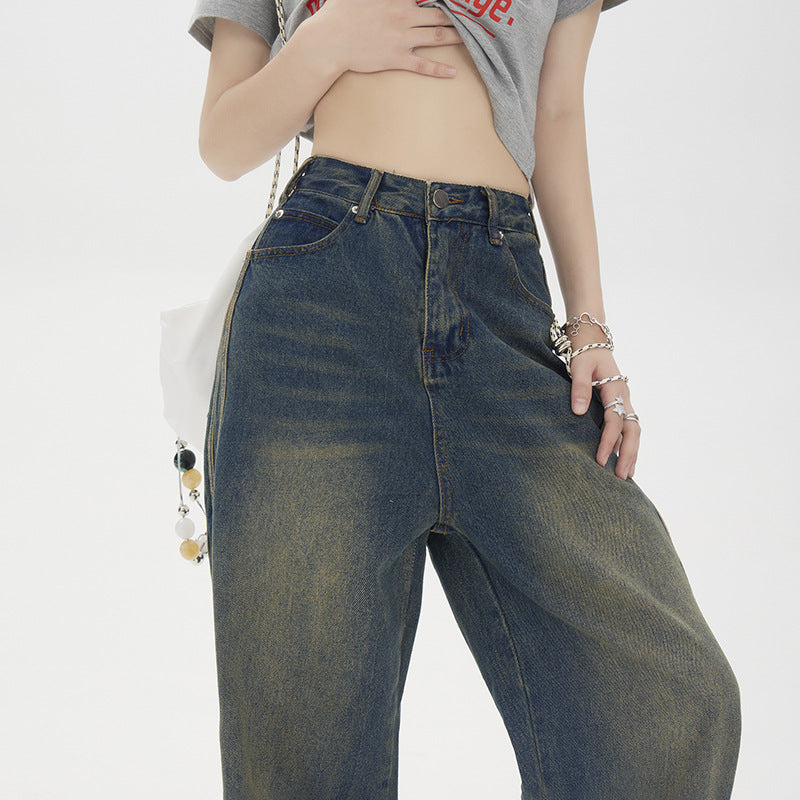 Close-up of high-waisted wide-leg jeans with decorative side stripes paired with cropped grey t-shirt and silver chain accessories