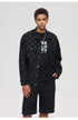Model wearing black checkered jacket with graphic tee and silver chain accent