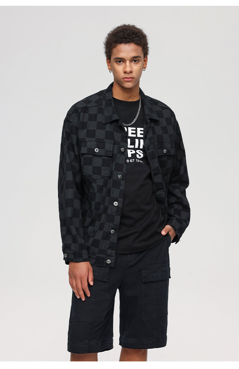 Model wearing black checkered jacket with graphic tee and silver chain accent