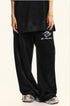 Lower body shot of black Backstairs sweatpants with logo and patterned sneakers