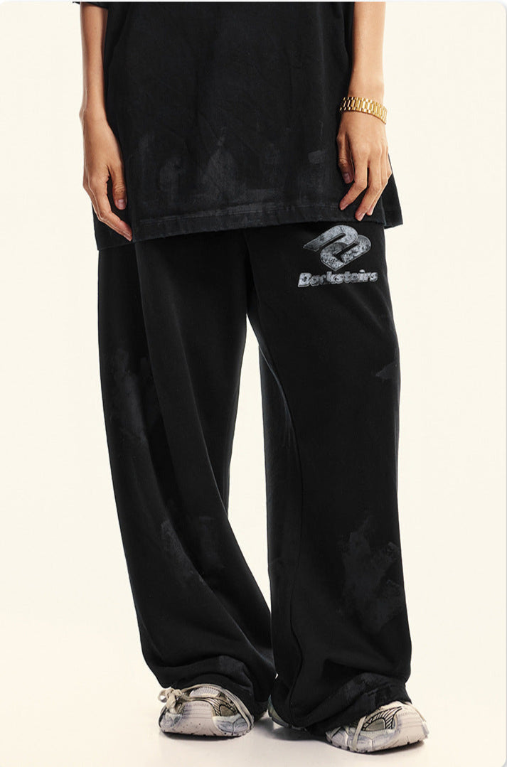 Lower body shot of black Backstairs sweatpants with logo and patterned sneakers