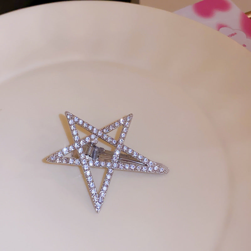 Rhinestone pentagram hair clip with a silver-tone metal frame, displayed on a white plate.