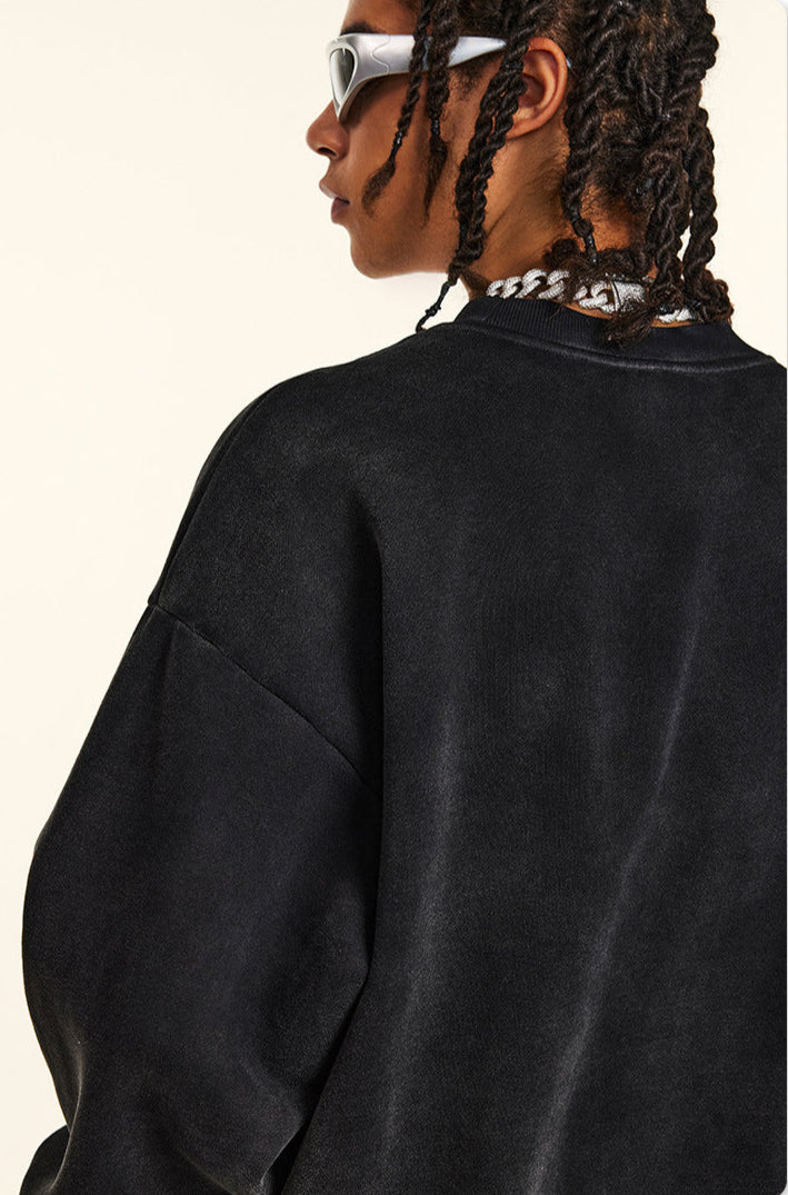 Close-up profile of model showing shoulder seam detail of black sweatshirt, twisted braids, white sunglasses, silver chain necklace visible