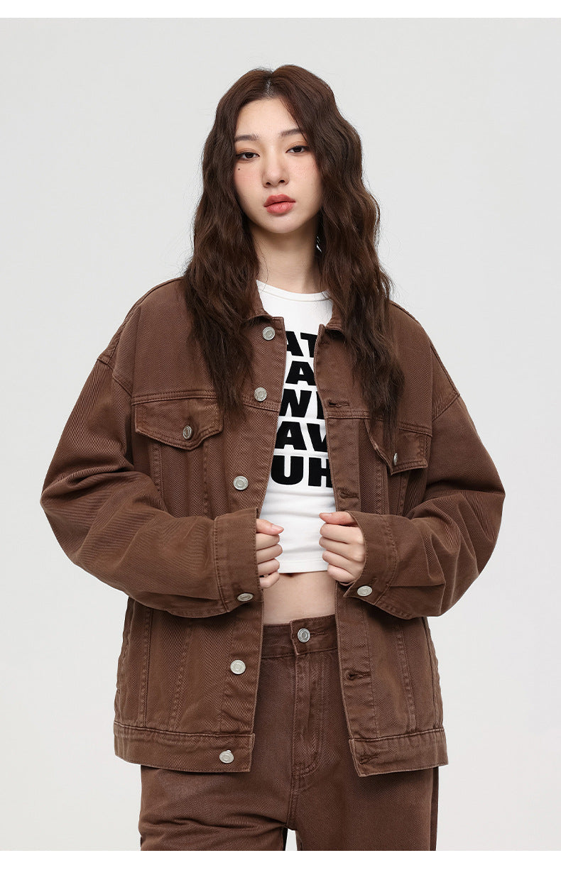 A woman wearing brown denim jacket with statement buttons over white graphic tee and matching pants 