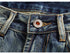 Close-up detail of jeans button with 'Jeans Fashion' branding and vintage wash denim texture