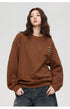 Woman with wavy brown hair looking to side, wearing brown textured sweatshirt and denim culottes