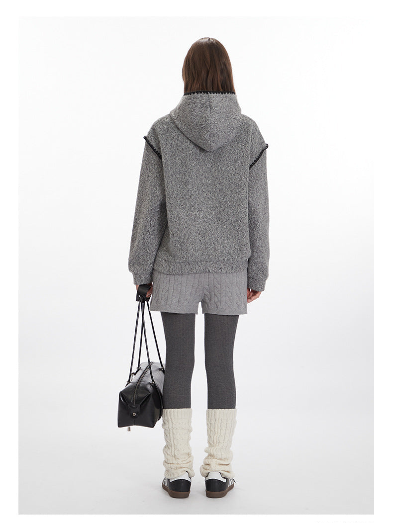 Back view of grey textured hoodie ensemble with cable knit shorts, dark grey leggings, cream leg warmers, and black sneakers. Accessorized with black leather handbag