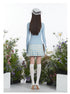 Back view showing slim-fit blue sweater and pleated gingham mini skirt, highlighting the skirt's A-line silhouette and white knee sock styling.